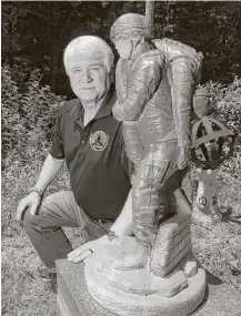  ?? Carlos Osorio photos / Associated Press ?? Former Army medic James McCloughan kneels next to a statue presented to him by a fellow soldier in South Haven, Mich. McCloughan saved the lives of 10 soldiers during a battle.