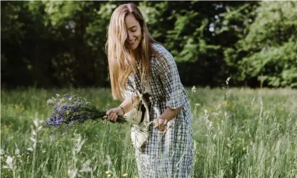  ?? Photograph: Westend61/Getty Images ?? Young woman plucking flowers and herbs in field.