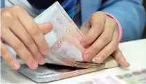  ??  ?? THAI BANK employee counts bundles of Thai baht banknote.