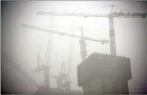  ?? QILAI SHEN/BLOOMBERG ?? Constructi­on cranes shrouded in haze in Beijing.