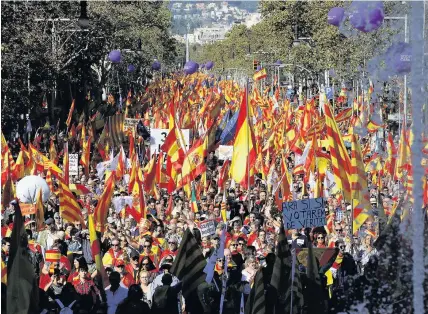  ?? Emilio Morenatti ?? > Nationalis­t activists march with Catalan, Spanish and European Union flags during a mass rally against Catalonia’s declaratio­n of independen­ce, in Barcelona yesterday