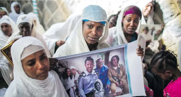  ?? THE ASSOCIATED PRESS ?? Snteayw Girmaw holds a photo of her sister Zemenech Bililin, wearing Israeli military uniform, during a solidarity event at a synagogue in Addis Ababa, Ethiopia. Zemenech Bililin has not seen her sisters in more than a decade, since she immigrated to...