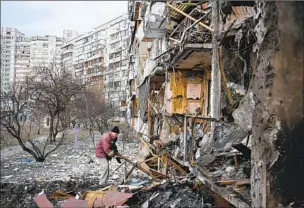  ?? Daniel Leal AFP/ Getty I mages ?? A MAN salvages items at a building near Kyiv, Ukraine’s capital, that was shelled last year.