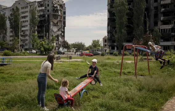  ?? Nicole Tung, © The New York Times Co. ?? Children play in a park surrounded by destroyed buildings Thursday in Borodyanka, Ukraine. As Moscow’s invasion approached its 100th day, President Volodymyr Zelensky said Russia now occupies one-fifth of Ukraine.