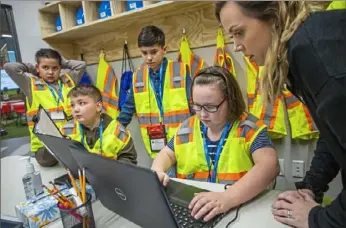  ??  ?? From left, David Chacon, 9, Matthew Furmanek, 10, Logen Hughes, 10, and Jenna Campbell, 9, are helped Tuesday by Maura Teti of Junior Achievemen­t, in the Mascaro Constructi­on storefront in JA’s BizTown.