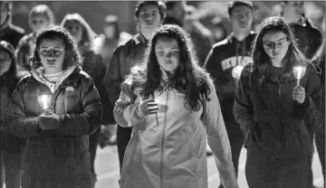  ??  ?? Led by high school students, mourners walk around the track of the football field with candles during a community vigil for the victims of Florida high school’s mass shooting. — AFP photo