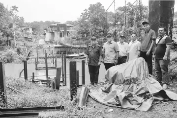  ??  ?? (From left) Jamit, Watson, Penghulu Pasang Tuba and others at the site of a steel bridge project across Sungai Kapit to link Rumah Nuang and Rumah Taba to Jalan Bukit Goram, which is now 45 per cent completed.