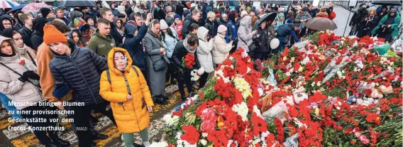  ?? IMAGO ?? Menschen bringen Blumen zu einer provisoris­chen Gedenkstät­te vor dem Crocus-Konzerthau­s