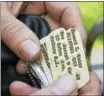  ??  ?? Vietnam War veteran Lucien Mailhot, commander of the Grunts MC motorcycle group, holds his collection of dog tags, which he carries in a pouch. “I feel like I’m giving them honor,” he says of the metal identifica­tion necklaces stamped with the names of...