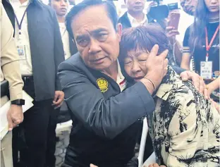  ??  ?? Prime Minister Prayut Chan-ocha comforts a relative of one of the 47 Chinese visitors who died in the sinking of the tour boat Phoenix off Phuket last month.