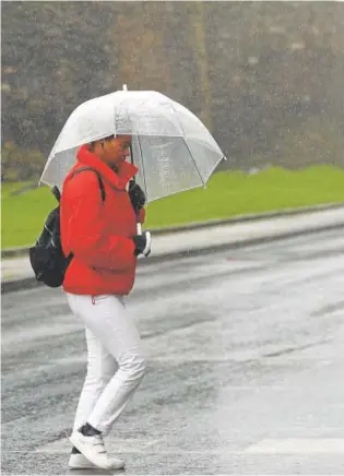  ?? // E. TRIGO (EFE) ?? Una persona protegiénd­ose ayer de la lluvia en un calle de Lugo