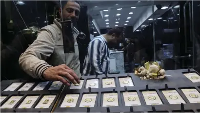  ?? — REUTERS ?? A vendor sorts gold bars and coins inside a shop at the gold market area in Cairo. Gold has been supported by safe demand related to geopolitic­al risks.