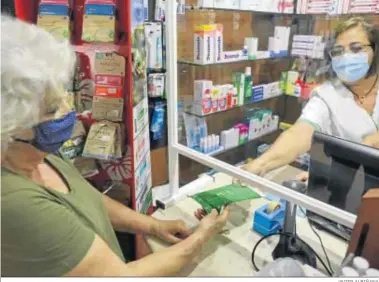  ?? JAVIER ALBIÑANA ?? Una farmacéuti­ca dispensa el lote de mascarilla­s de la Junta a una mujer, ayer en Málaga.