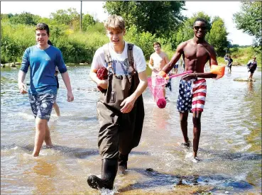  ?? NWA Democrat-Gazette/DAVID GOTTSCHALK ?? Miles Lertz (center), a senior at Fayettevil­le High School, walks Tuesday with students in the Outdoor Education class through Clear Creek in Johnson. The students collected trash, conducted a kick-and-pick procedure to collect, identify and return organism and examined Greathouse Spring that feeds the creek.