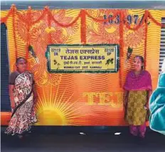  ?? AFP ?? Passengers pose for a photograph alongside the Tejas train during its inaugural run between Mumbai and Goa at Ratnagiri. Monday’s first run appeared to go down well with locals — although foreign visitors wanting a more traditiona­l train experience may...