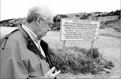  ?? — Photo by Colin Maclean/the Telegram ?? Torbay Mayor Bob Codner walks past a sign on Torbay Beach on Sunday. The beach has been closed to the public since a nearby sewer pipe ruptured in 2009. Codner hopes to be able to move forward with replacing the town’s outdated sewer processing system...