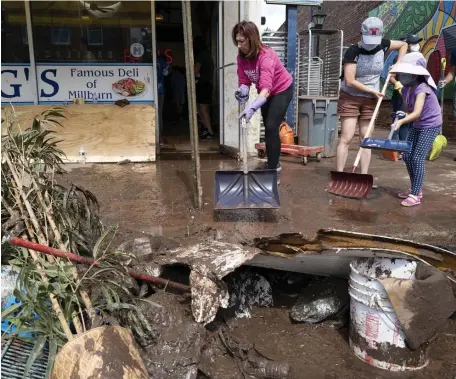  ?? Ap pHotos ?? CLEANUP TIME: Volunteers, employees and family members move water and mud to the sidewalk from Goldberg’s Famous Deli in Millburn, N.J., on Saturday after the shop was flooded by the arrival of the remnants of Hurricane Ida. Below, debris is removed from the basement of Goldberg’s.