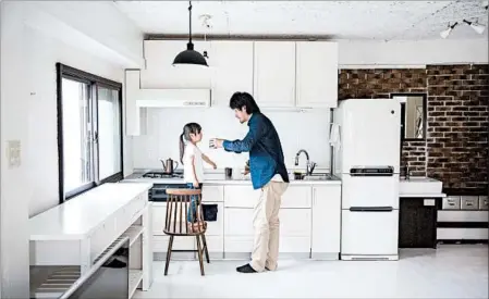  ?? SHIHO FUKADA/PHOTOS FOR THE WASHINGTON POST ?? Naoki Numahata, with daughter Ei, believes in keeping his tiny Tokyo apartment free of clutter. He and his wife keep nothing on the kitchen counter.
