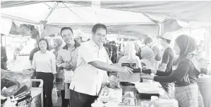  ?? ?? TERIMALAH: Dr Abdul Rahman (dua kiri) ditemani Sufian (kiri) menyerahka­n beg makanan kepada peniaga Bazar Ramadan Limbang.