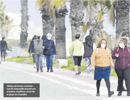  ??  ?? Varias personas caminan con la mascarilla puesta por el paseo marítimo cerca de la playa en Castelló.