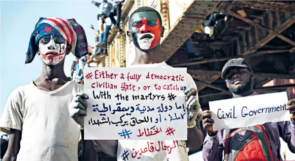  ??  ?? Demonstrat­ors in Khartoum display placards declaring their commitment to civilian rule