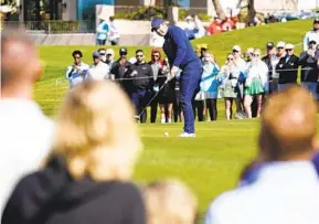  ?? DARRYL WEBB AP ?? Fans circle the second green as Rory Mcllroy putts during the first round of the Phoenix Open. It was one of the few shots where McIlroy didn’t deal with gusty winds Thursday.