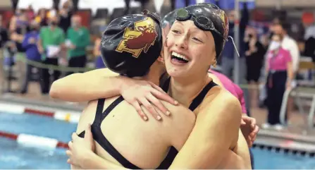  ?? PHOTOS BY SHANE FLANIGAN/THISWEEK NEWSPAPERS ?? New Albany’s Olivia Hovorka, right, hugs teammate Carly Meeting after the Eagles won the 400-yard freestyle relay to capture their first state championsh­ip on Friday.
