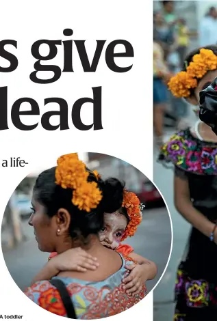  ??  ?? A toddler embraces her mother at a Day of the Dead parade in Juchitan, Mexico.