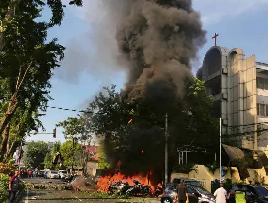  ?? Antara Foto/Reuters ?? Motociclet­as estacionad­as à frente da Igreja Pentecosta­l Central de Surabaya pegam fogo após atentado a bomba ocorrido no domingo