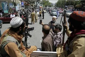  ?? Rahmat Gul/Associated Press ?? Afghans take a selfie with Taliban fighters during patrols in the city of Kabul, Afghanista­n, on Thursday. The Taliban celebrated Afghanista­n’s Independen­ce Day by declaring they beat the U.S., but challenges to their rule began to emerge.