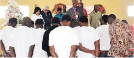  ?? CONTRIBUTE­D ?? Minister of religion Sylvester Lindo (centre), prison ministry team member at Food For The Poor, prays for the freed inmates of the St Catherine Adult Correction­al Centre while representa­tives of the charity and prison officials look on.