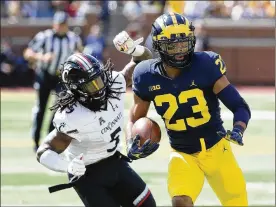  ?? LEON HALIP / GETTY IMAGES ?? Cincinnati’s Mike Boone can’t prevent Michigan’s Tyree Kinnel from returning an intercepti­on for a touchdown during the first quarter.