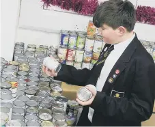  ?? ?? Sam Nightingal­e, 14, helping to sort through the thousands of tins.