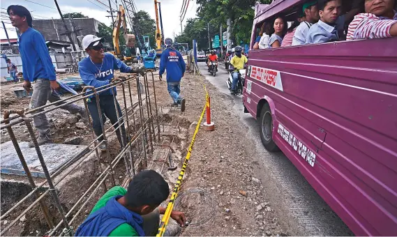  ?? SUNSTAR FOTO / AMPER CAMPAÑA ?? HOW’S IT GOING? One of the men working on an underpass on N. Bacalso Ave. in Cebu City seems to be amused by something (or someone) passing by the area, where the traffic often isn’t something to smile about.