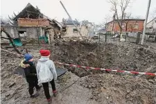  ?? Mykola Tys/Associated Press ?? Children look at a crater created by an explosion after Russian shelling in a residentia­l area of Solonka, Lviv region, Ukraine.