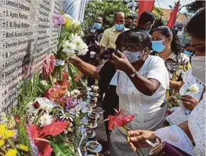  ?? AFP PIC ?? People placing flowers in front of a memorial plaque commemorat­ing the people who died in the 2019 Easter Sunday bombing at St Sebastian’s church in Katuwapiti­ya, Sri Lanka, yesterday.