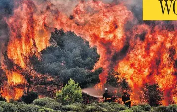  ?? ANGELOS TZORTZINIS/AFP/GETTY IMAGES ?? Firefighte­rs work to extinguish flames in the village of Kineta, near Athens, on Tuesday. Raging wildfires have killed scores of people, devouring homes and forests and forcing terrified residents to flee into the sea to escape danger.