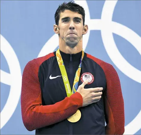  ?? Christophe Simon/AFP/Getty Images ?? Gold medallist Michael Phelps listens to the national anthem on the podium after the men's 200-meter individual medley final Thursday in Rio. The win gave him a 22nd gold medal in his career.