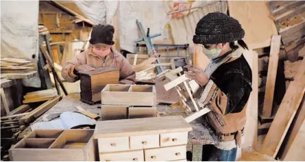  ?? JUAN KARITA/AP ?? Hector Delgado’s children, wearing masks to curb the spread of the coronaviru­s, work in the family’s workshop in El Alto, Bolivia.