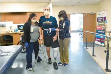 ?? ?? John Bysiewicz learns how to walk with a prosthetic leg during a physical therapy session with physical therapist Paula Savino, right, and occupation­al therapist Jaclyn Lavigne at Gaylord Hospital on Thursday in Wallingfor­d. Bysiewicz, director of the New Haven Road Race, was severely injured by a hit-and-run driver while riding his bicycle on Nov. 12 in Guilford.