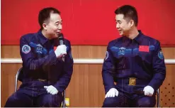  ?? —AP ?? CHINA: Chinese astronauts Jing Haipeng, left, and Chen Dong, right, chat behind a glass enclosure during a presser at the Jiuquan Satellite Launch Center in northwest China yesterday.