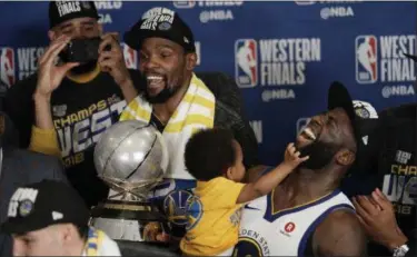  ?? DAVID J. PHILLIP — ASSOCIATED PRESS ?? The Warriors’ Kevin Durant holds the Western Conference trophy as he and Draymond Green celebrate with teammates after defeating the Rockets in Game 7.