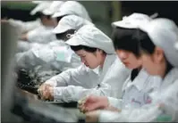  ?? WANG YISHU / FOR CHINA DAILY ?? Foxconn employees work at a production facility in Shenzhen, Guangdong province.