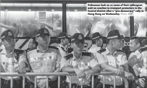  ?? Photo: AFP ?? Policemen look on as some of their colleagues wait on coaches to transport protesters in the Central district after a “pro-democracy” rally in Hong Kong on Wednesday.