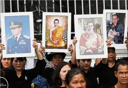  ?? — AP ?? Goodbye, dear king: Thai mourners holding up portraits of Bhumibol near the Grand Palace in Bangkok.