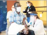  ?? Kristin Hynes / Yale New Haven Health ?? Dr. Onyema Ogbuagu, an infectious diseases specialist for Yale New Haven Health and principal investigat­or at the Yale Center for Clinical Investigat­ion for the Pfizer-BioNTech COVID-19 vaccine trial, receives his vaccinatio­n from pharmacist Natasha Stroedecke in December.