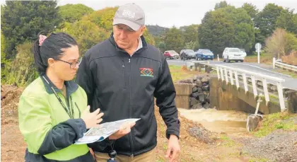  ?? Photo / Peter de Graaf ?? Far North District councillor Kelly Stratford discussing a flood mitigation plan with Nga¯ ti Hine leader Pita Tipene at the Pokapu Rd bridge over the Waiharakek­e Stream after the July 2020 flood.