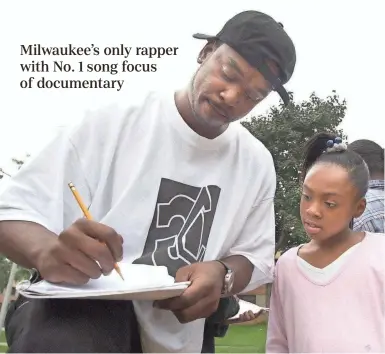  ?? JOURNAL SENTINEL FILES ?? Rap artist Coo Coo Cal signs an autograph for Rodneca Hampton, 9, while he visits his old neighborho­od in 2001, near North 60th Street and West Silver Spring Drive. A month before, Cal’s single “My Projects” hit No. 1 on the Billboard Hot Rap Songs chart.