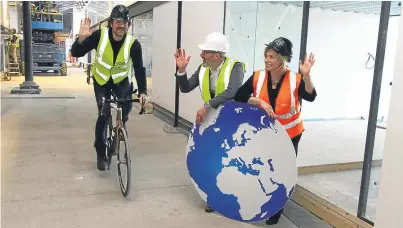  ??  ?? Entreprene­urial Scotland chairman Chris van der Kuyl rides Mark Beaumont’s world record breaking bike at Water’s Edge, Dundee, as John Robertson and Amanda Robertson look on.