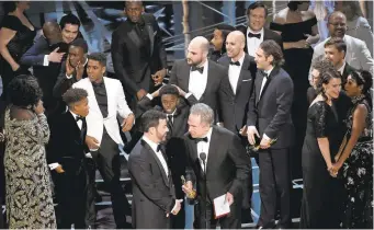  ?? CHRIS PIZZELLO/INVISION VIA ASSOCIATED PRESS ?? Host Jimmy Kimmel, left, and presenter Warren Beatty discuss the mistaken reading of the winner for best picture as the casts and producers of “La La Land” and “Moonlight” mingle on stage. “Moonlight” was the real winner.